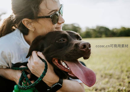 女子拥抱微笑的黑狗享受户外时光