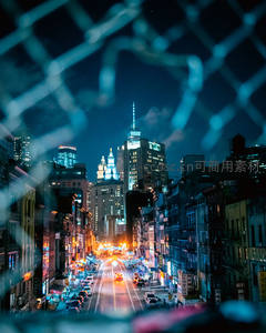 铁丝网后霓虹闪烁的城市街景