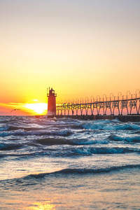 夕阳海浪拍打延伸防波堤灯塔