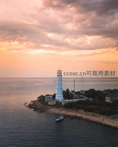 夕阳下海边灯塔与归航小船