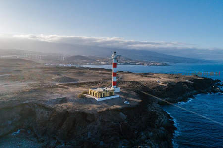 灯塔俯瞰海湾，远山风车点缀地平线