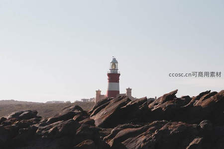 红白灯塔屹立礁石之上，晴空万里
