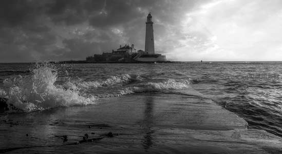 黑白海浪拍打灯塔，孤岛上的守望者