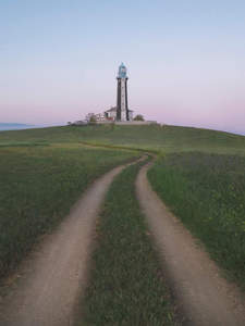 绿野小径通向山顶灯塔的宁静黄昏