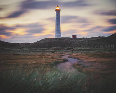 夕阳下草原小径通向发光灯塔