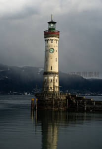 阴云密布下的湖畔古灯塔，倒影如画