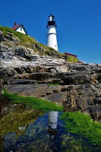 海岸灯塔倒影在碧水绿藻间