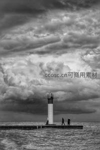 黑白光影下的码头灯塔与垂钓者