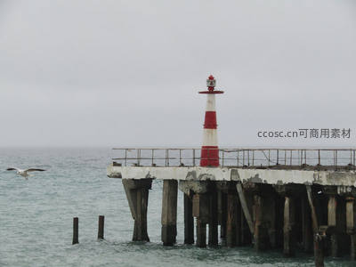 锈迹斑驳的旧码头与红白灯塔相伴