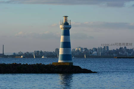 蓝白条纹灯塔守望港湾，城市天际线作背景