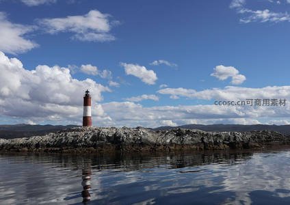 蓝天白云下，孤岛灯塔倒影如画