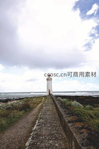 长堤通向海边灯塔，云层密布浪花翻涌