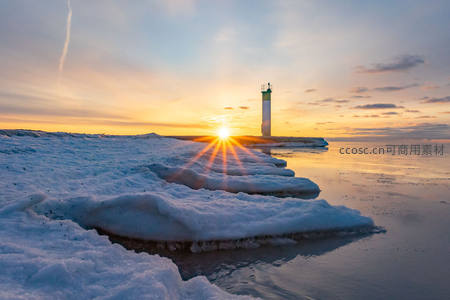 冰封海岸日出时，灯塔剪影耀金辉