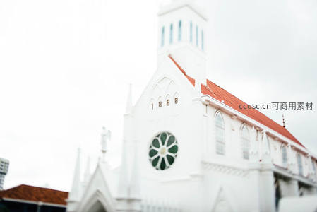 白色哥特教堂玫瑰窗映衬红瓦屋顶