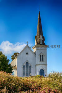 白色尖顶教堂矗立蓝天花丛间