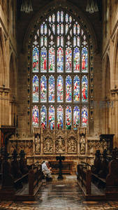 哥特教堂彩色玻璃窗与虔诚祷告者