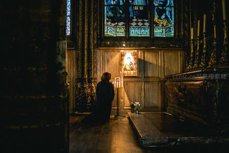信徒跪拜于彩色玻璃窗前祈祷