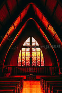 红色光影中耶稣像映衬彩色玻璃窗