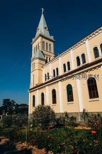米色教堂高塔映衬深蓝天空与花圃