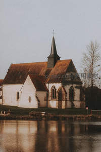 河畔古教堂静谧伫立，尖塔倒影水波间