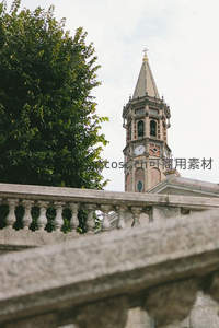 钟楼尖塔透过绿树与石栏隐约可见