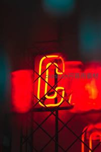 霓虹灯管在铁网后散发温暖红光