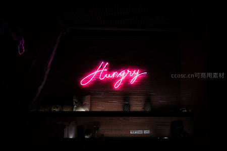 粉红霓虹“Hungry”悬于木质吧台暗影之中
