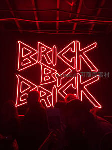 红色霓虹灯牌‘BRICK BY BRICK’夜景