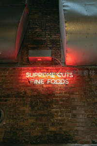 红光霓虹招牌映照砖墙夜景