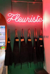 花店墙上粉红霓虹灯与悬挂围裙