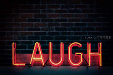 砖墙前红色霓虹‘LAUGH’字样