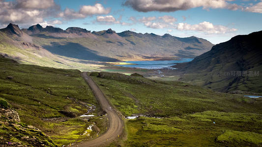 蜿蜒山路穿越翠绿山谷与远山湖泊