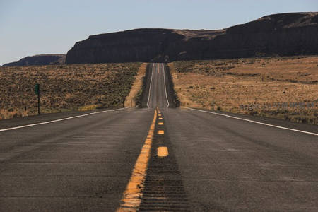 荒漠公路上黄线引导视线通向悬崖