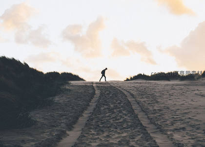 孤独行者踏沙归途，夕阳剪影映苍茫