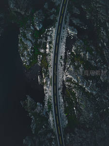 航拍视角下，公路如丝带穿越崎岖岩岸