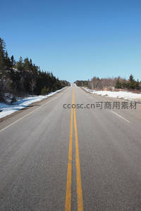 晴空下穿越雪地森林的笔直公路