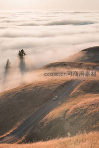 晨雾缭绕山丘公路上孤独行驶的汽车