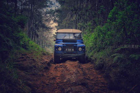 蓝色越野车穿越森林泥泞小径