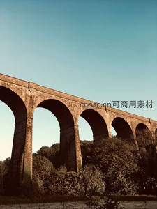 古老石拱桥横跨林间，蓝天映衬显雄伟