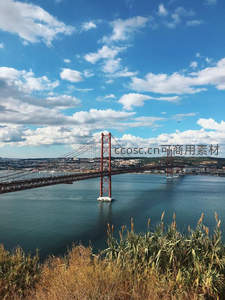 蓝天白云下的红色悬索桥横跨碧水