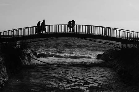 黑白剪影行人漫步于海边拱桥