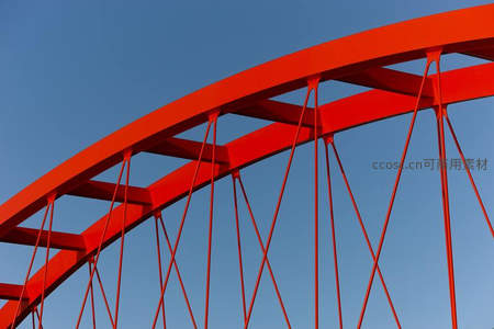红色拱桥结构在蓝天下的几何之美