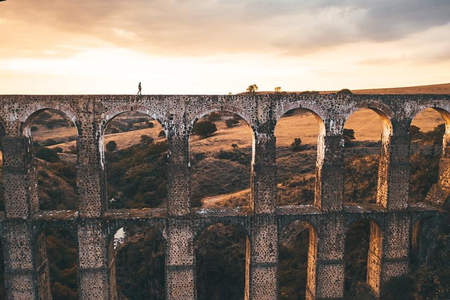 古老石砌高架渠上孤独行者剪影