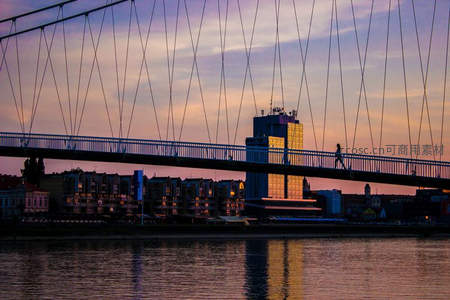 斜拉桥剪影映晚霞，城市天际线灯火初上