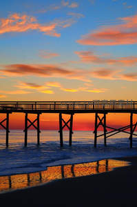 夕阳下的海滨栈桥剪影，天空云霞绚烂如画