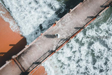 航拍码头人独立，浪花飞溅显孤寂