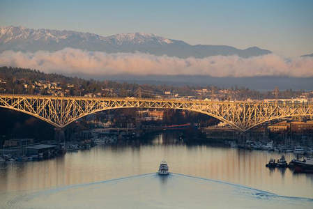 雪山云海下桥梁横跨，游船划破平静湖面