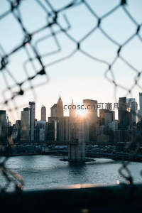 透过铁丝网看日落时分的城市剪影