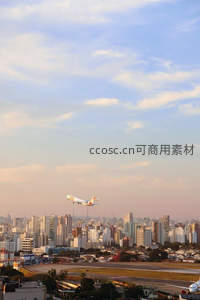 城市上空飞机掠过，高楼林立日落时分