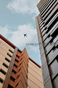飞机掠过楼宇间缝隙，飞向蔚蓝天空